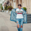 Attractive girl in a jeans jacket and white t-shirt walking along the street. Mock-up. FIESTAS PATRIAS
